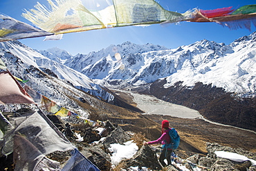 A woman trekking in the Langtang valley in Nepal stands on the top of Kyanjin Ri and looks out towards Ganchempo in the distance, Langtang Region, Himalayas, Nepal, Asia