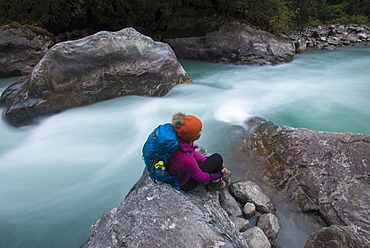 A woman takes a break from the trail and sits beside the Langtang Khola near the little village of Riverside on a misty evening, Langtang Region, Nepal, Asia