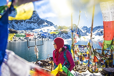 A trekker stands among prayer flags beside the holy lakes at Gosainkund in the Langtang region, Himalayas, Nepal, Asia