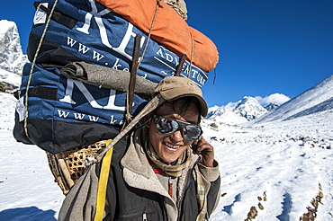 A Sherpa near Dingboche hauling gear to Everest Base Camp for the climbing expeditions stops for a quick rest, Khumbu Region, Nepal, Asia