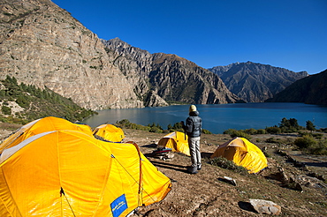 A trekker looks out at the turquoise blue Phoksundo Lake, Dolpa Region, Nepal, Asia