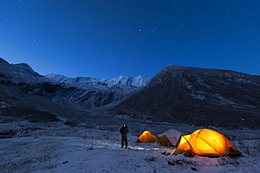 A man standing outside his tent on a cold night in the little explored Juphal Valley in the remote Dolpa region, Nepal, Asia