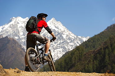 A mountain biker in the Tsum Valley looks at Ganesh Himal mountains, Manaslu region, Himalayas, Nepal, Asia