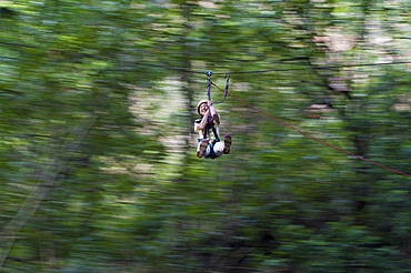 A girl clings on and laughs with delight on a zip line, Nepal, Asia