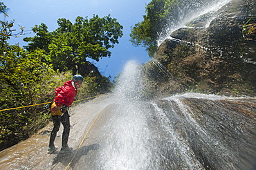 A man pauses to smile for the camera while canyoning in a waterfall, Nepal, Asia