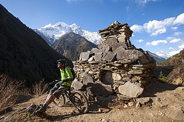 A mountain biker in the Tsum Valley stops to check out the view, Nepal, Asia