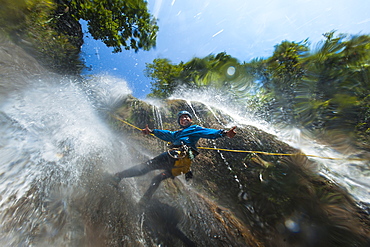 A man pauses to smile for the camera while canyoning in a waterfall, Nepal, Asia