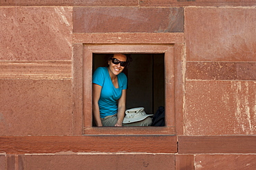 A tourist peeks out from one the windows within the Fatehpur Sikri temple complex, Uttar Pradesh, India, Asia