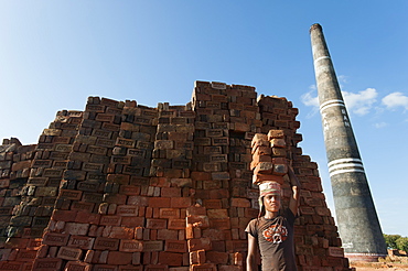 A young man carries a pile of bricks on his head at a brick factory, Chittagong Hill Tracts, Bangladesh, Asia