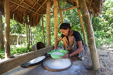 A woman mills grain into flour using a tradiional mill, Chittagong Hill Tracts, Bangladesh, Asia