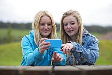 Girls reading a smartphone, England, United Kingdom, Europe