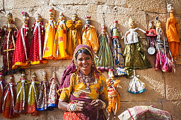 A woman sells puppets along the fort walls in Jaisalmer in the desert state of Rajasthan, India, Asia