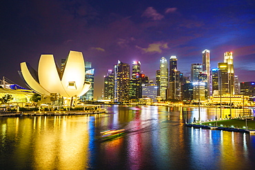 The lotus flower shaped ArtScience Museum overlooking Marina Bay with the city skyline beyond illuminated at night, Singapore, Southeast Asia, Asia