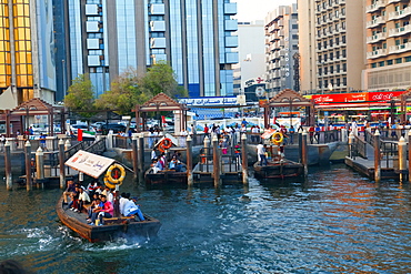 A water taxi carrying passengers arrives at a busy dock, Dubai Creek, Dubai, United Arab Emirates, Middle East