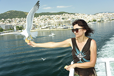 Woman feeding seagulls on a ferry from Kavala to Thassos, North Aegean Sea, Greek Islands, Greece, Europe