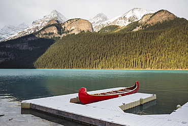 Red canoe and dock in Lake Louise with snow-covered mountains, Banff National Park, UNESCO World Heritage Site, Alberta, The Rockies, Canada, North America