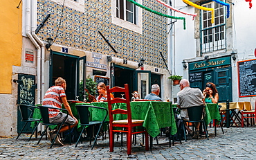 Tourists on a terrace of a restaurant serving traditional Portuguese food in the old district of Alfama, Lisbon, Portugal, Europe