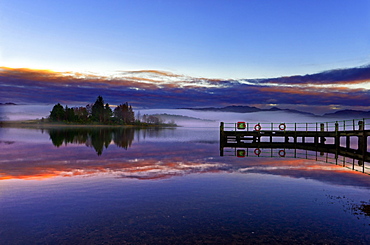 A tranquil view across the calm waters of Loch Shiel as dawn breaks on a misty winter morning. Ardnamurchan, Scottish Highlands, Scotland, United Kingdom, Europe