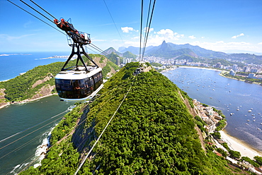 A motion blurred cable car approaches the station atop Sugarloaf mountain, with sweeping view of Rio de Janeiro behind, Rio de Janeiro, Brazil, South America