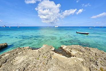 Rocky coastline in Cayman Islands with fishing boat in the transparent blue water, Cayman Islands, West Indies, Caribbean, Central America