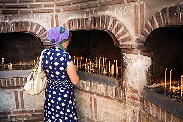 A female worshiper lights a candle outside the Biserica Sfantul Anton in Bucharest, Romania, Europe