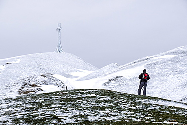 Hiker reaching the summit cross of Monte Catria in winter, Apennines, Umbria, Italy, Europe