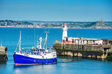 Fishing boat coming into the harbour at the village of Newlyn with St. Michael's Mount at Marazion in the distance, Cornwall, England, United Kingdom, Europe