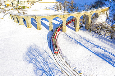 Bernina Express passes under the helical (spiral) viaduct of Brusio, UNESCO World Heritage Site, Valposchiavo, Canton of Graubunden, Switzerland, Europe