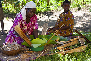 A woman wraps some groundnuts in a banana leaf, Uganda, Africa