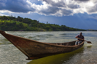 A man paddles a wooden dugout canoe at the source of the River Nile in Uganda, Africa