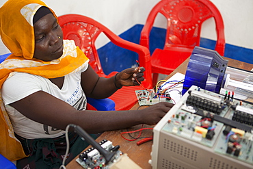 A female solar engineer, known as a solar mama, works on the printed circuit board of a solar lamp, Tanzania, East Africa, Africa