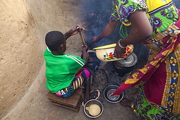 A young girl helping her mother cook at their home in Tinguri, Ghana, West Africa, Africa