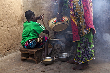 A young girl helping her mother cook at their home in Tinguri, Ghana, West Africa, Africa