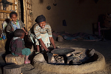 A woman lighting a fire in her home so she can cook dinner, Ethiopia, Africa