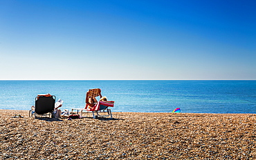 People relaxing on deckchairs on the beach, Brighton, East Sussex, England, United Kingdom, Europe