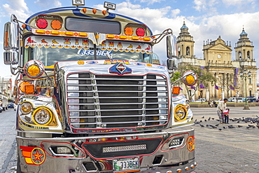 A typical chicken bus standing at the main square of Guatemala City with view to the Metropolitan Cathedral in the background, Guatemala City, Guatemala, Central America