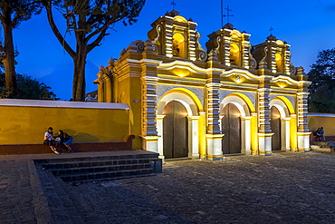 Illuminated entrance gate of the chapel El Calvario near Antigua at dusk, Guatemala, Central America