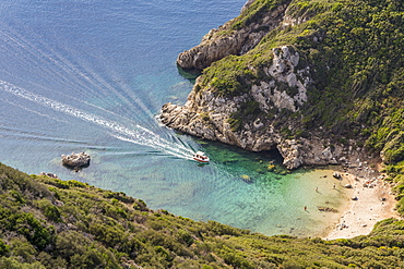 High-angle view down to one of the Porto Timoni beaches and a taxi boat approaching the bay, Afionas, Corfu, Greek Islands, Greece, Europe