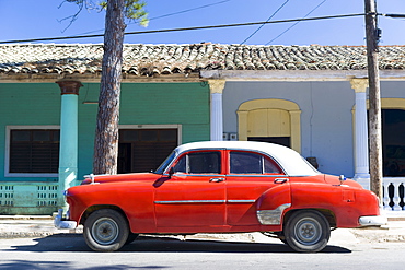 Red vintage American car parked on street next to colourful buildings in Vinales, Cuba, West Indies, Caribbean, Central America