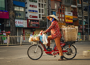 Vietnamese woman on bike crossing the road, Ho Chi Minh City, Vietnam, Indochina, Southeast Asia, Asia