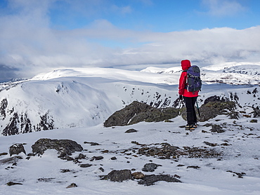 A winter walker on the summit of The Cairnwell in the Cairngorm National Park looking over to Carn a' Gheoidh, Cairngorm National Park, Scotland, United Kingdom, Europe