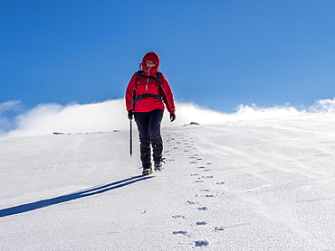 Female winter walker descending a fresh snowy slope in the Cairngorm National Park, Scotland, United Kingdom, Europe