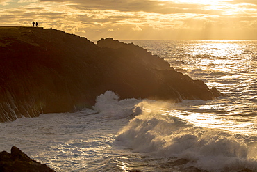 A couple enjoy the view of sunset and crashing waves, Newport, Oregon, United States of America