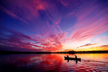 Two paddlers in a canoe on a lake at sunset, Ely, Minnesota, United States of America