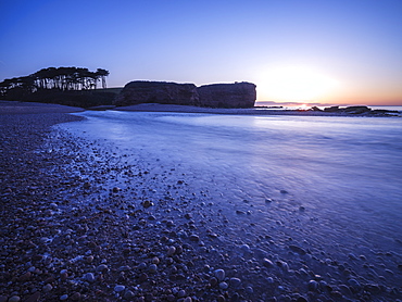 Sunrise behind the silhouetted cliff of Otter Head, where the River Otter meets the sea at Budleigh Salterton, Devon, England, United Kingdom, Europe