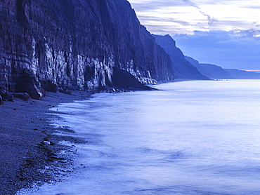 Soft glow of wet rock in pre-dawn twilight on the statuesque Jurassic Coast cliffs at Sidmouth, Devon, England, United Kingdom, Europe