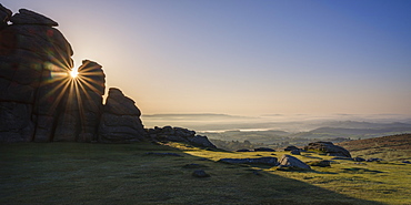 Sun breaks through a gap in granite rocks at Haytor in Dartmoor National Park, Bovey Tracey, Devon, England, United Kingdom, Europe