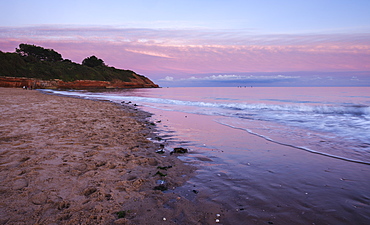 A passing weather front is attractively lit after sunset, with four SUP riders on the water, Orcombe Point, Exmouth, Devon, England, United Kingdom, Europe