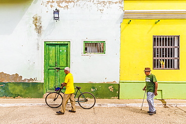 Local men walking past typically colourful colonial architecture in Trinidad, Cuba, West Indies, Caribbean, Central America