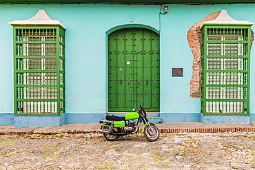 A motorbike in a typically colourful colonial street in Trinidad, Cuba, West Indies, Caribbean, Central America